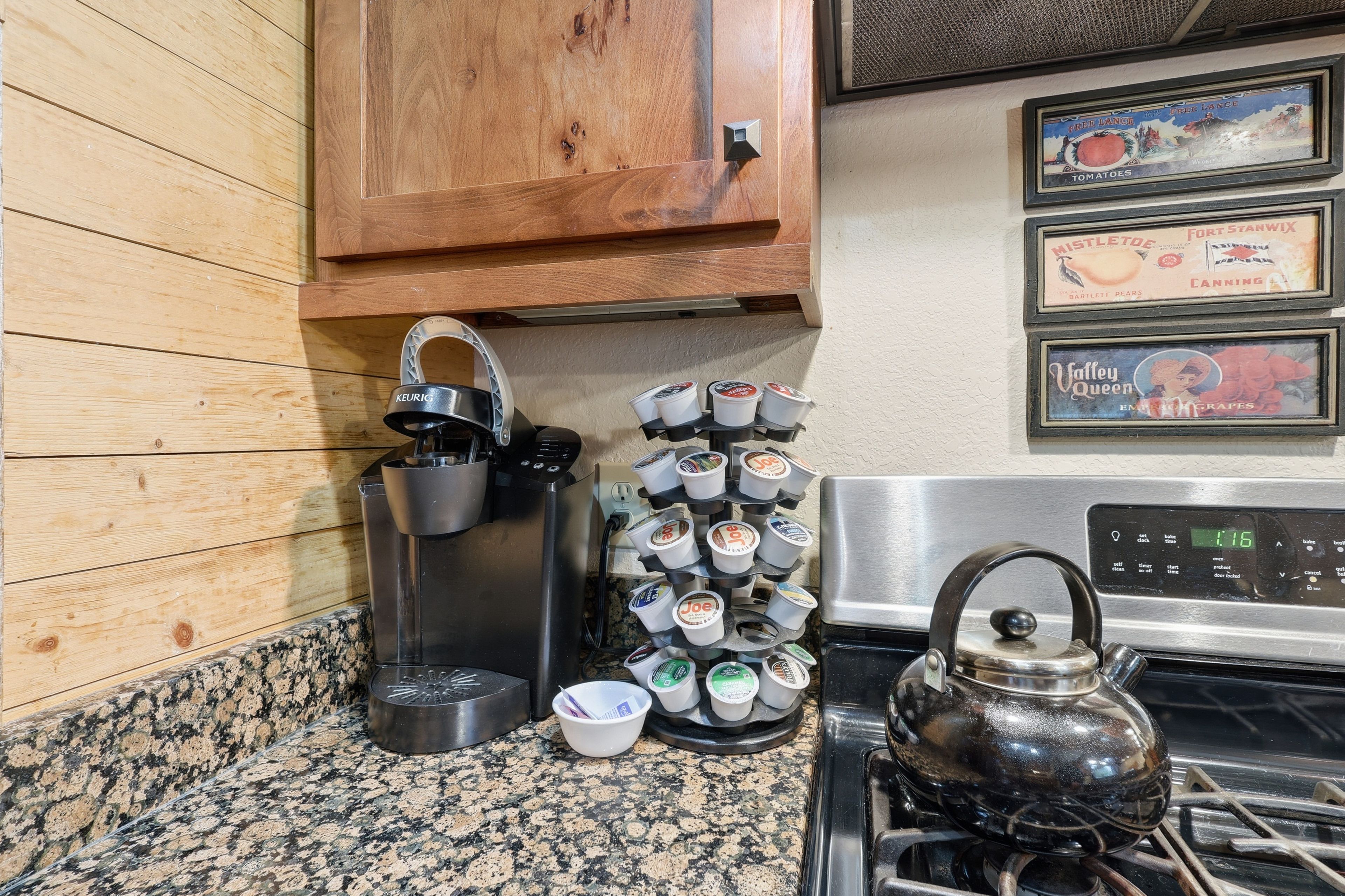 A kitchen with a coffee maker, a kettle, and a mug rack.