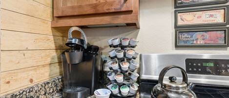 A kitchen with a coffee maker, a kettle, and a mug rack.