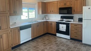 A kitchen with wooden cabinets, a stove, a microwave, and a refrigerator. - Great Space for Relaxing, Roomy House. Trailer Parking Plentiful, 3 Acres (South Fork)