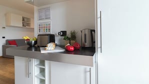 A modern kitchen with a stainless steel countertop, a toaster, a kettle, and a bowl of fruit. - Italianway Comfort - Gioia 59 (Milan)
