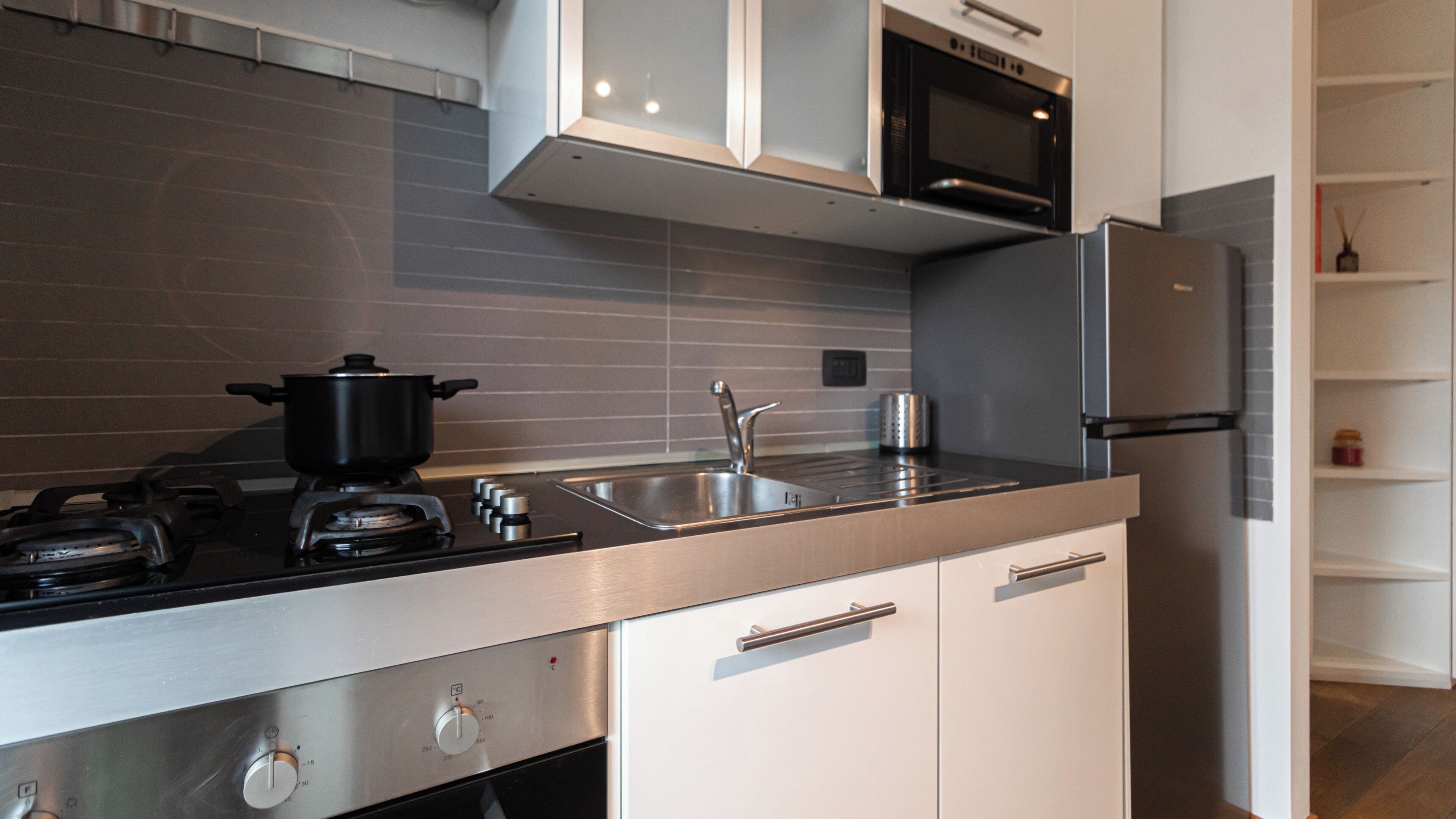 Una cocina moderna con electrodomésticos de acero inoxidable, una estufa a gas, un microondas y un horno empotrado.