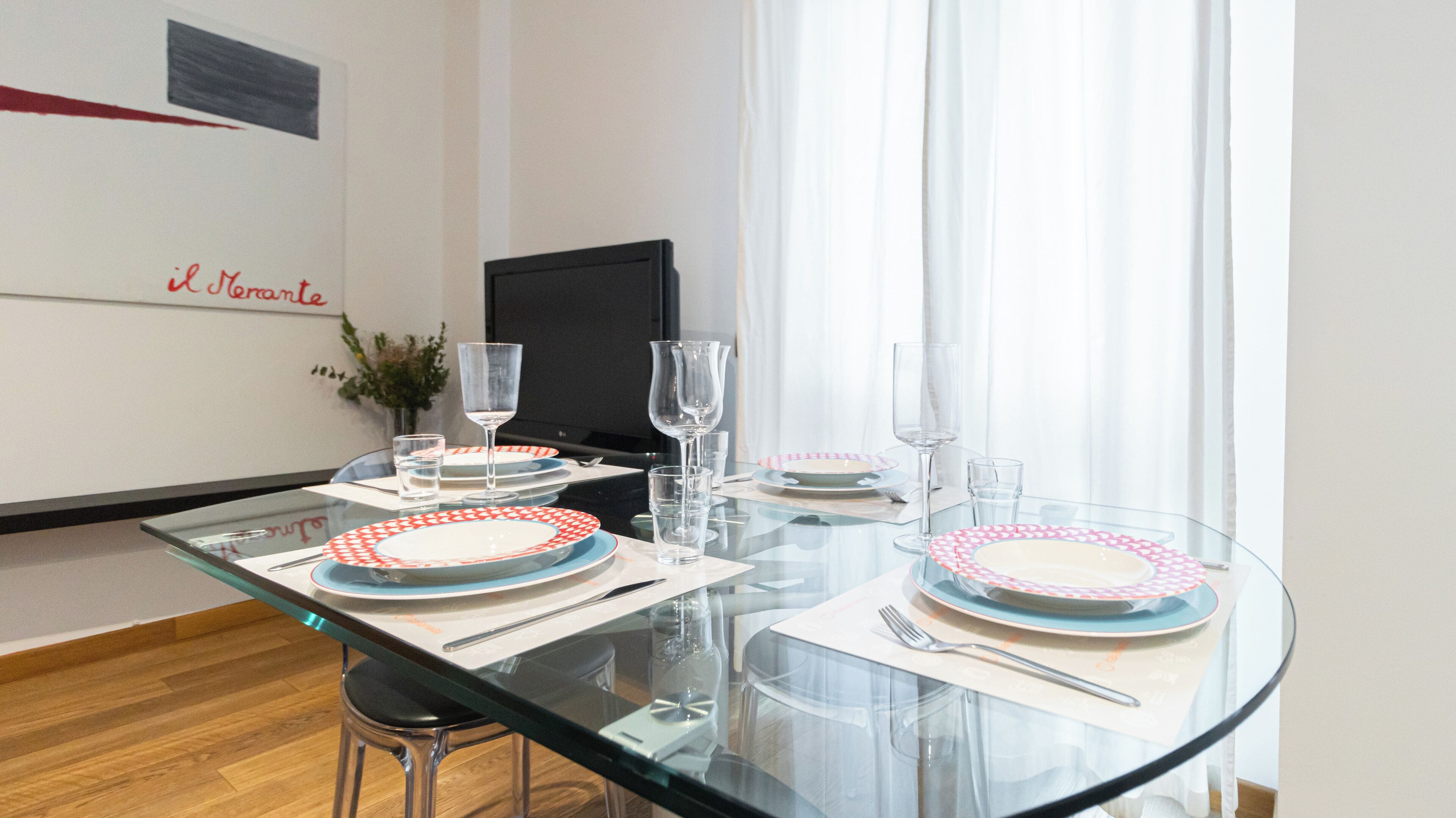A dining table set with plates, glasses, and cutlery, with a chair in front.