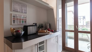 A kitchen with a bread bin, a bowl of fruit, a toaster, and a kettle. There are recycling bins and a plant on the counter. - Italianway Comfort - Gioia 59 (Milan)