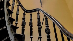 Una scala a chiocciola con ringhiera in metallo e parete color crema.