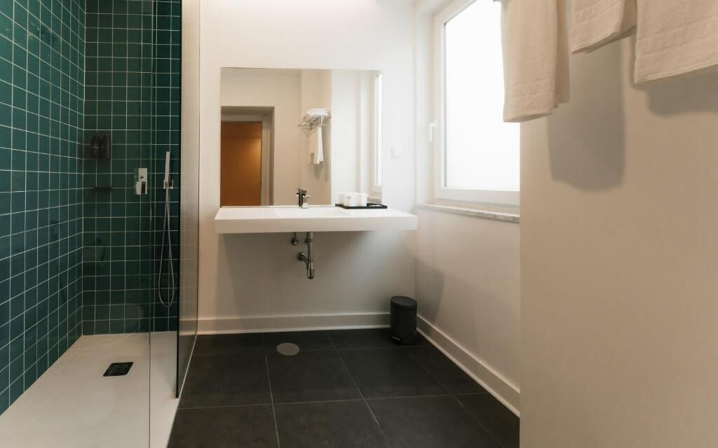Une salle de bain avec un lavabo blanc, un miroir et une fenêtre.