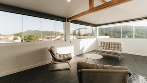 Une pièce spacieuse dotée de grandes fenêtres, d’un plafond haut avec des poutres apparentes et d’un aménagement moderne.