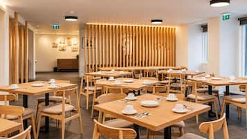 A modern dining area with wooden tables and chairs, equipped with white tableware.