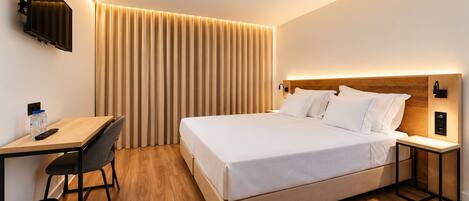 Ein modernes Hotelzimmer mit Bett, Nachttischen, Schreibtisch und Sessel.