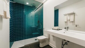 Une salle de bain moderne avec un lavabo blanc, des toilettes blanches et une douche aux carreaux bleus.