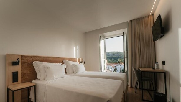 Une chambre d’hôtel avec deux lits, un bureau, une télévision et une vue sur le paysage urbain.