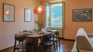 A dining area with a wooden table, chairs, a potted plant, and framed artwork on the walls. - Cernobbio in Riva. Lake views, Steps from Lake. (Cernobbio)