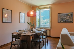 A dining area with a wooden table, chairs, a potted plant, and framed artwork on the walls. - Cernobbio in Riva. Lake views, Steps from Lake. (Cernobbio)