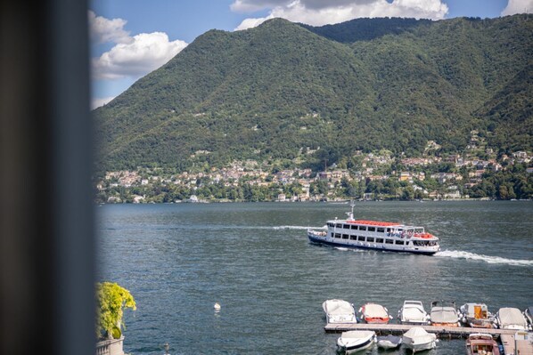 A lake with a boat, docked boats, and a mountainous backdrop. - Cernobbio in Riva. Lake views, Steps from Lake. (Cernobbio)