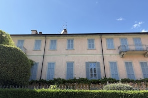 A multi-story building with a symmetrical facade, evenly spaced windows with shutters, and a balcony on the right side. - Cernobbio in Riva. Lake views, Steps from Lake. (Cernobbio)