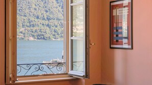 A room with a window overlooking a body of water and a forested hillside. - Cernobbio in Riva. Lake views, Steps from Lake. (Cernobbio)