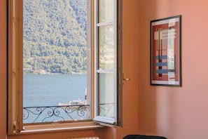 A room with a window overlooking a body of water and a forested hillside. - Cernobbio in Riva. Lake views, Steps from Lake. (Cernobbio)