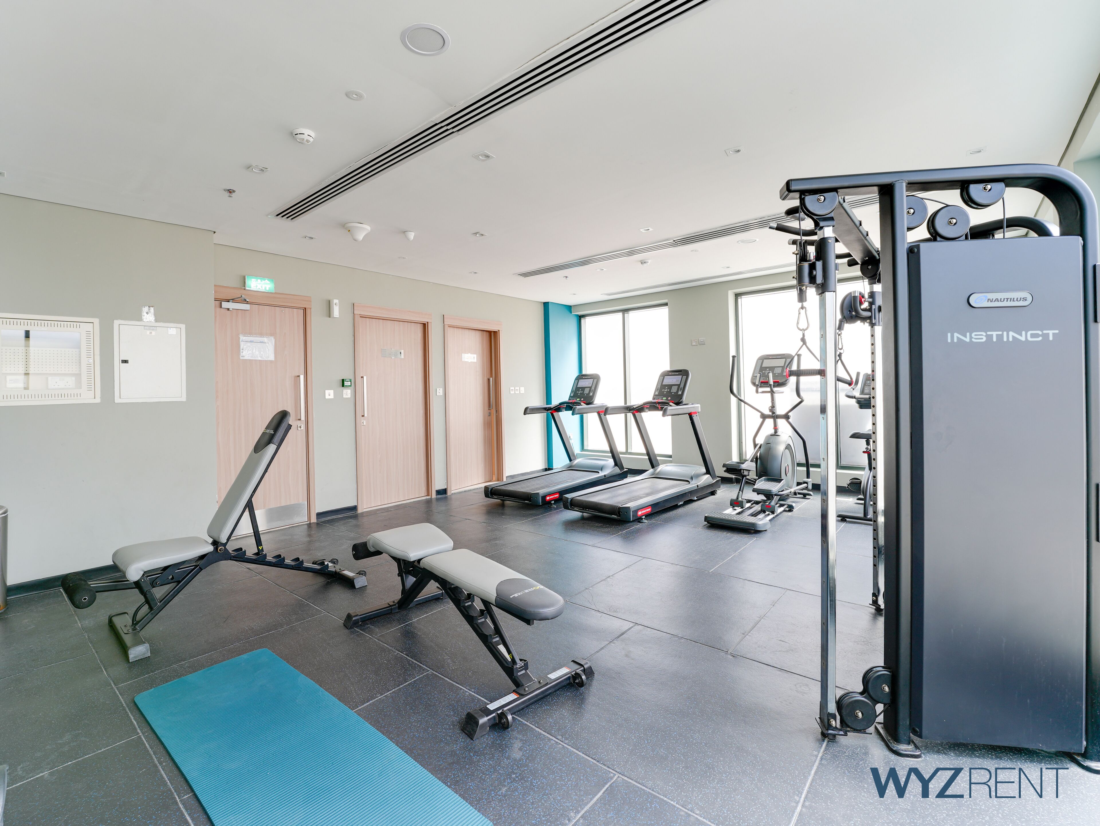 Un gimnasio con cintas de correr, una prensa de banca y una máquina Nautilus Instinct.