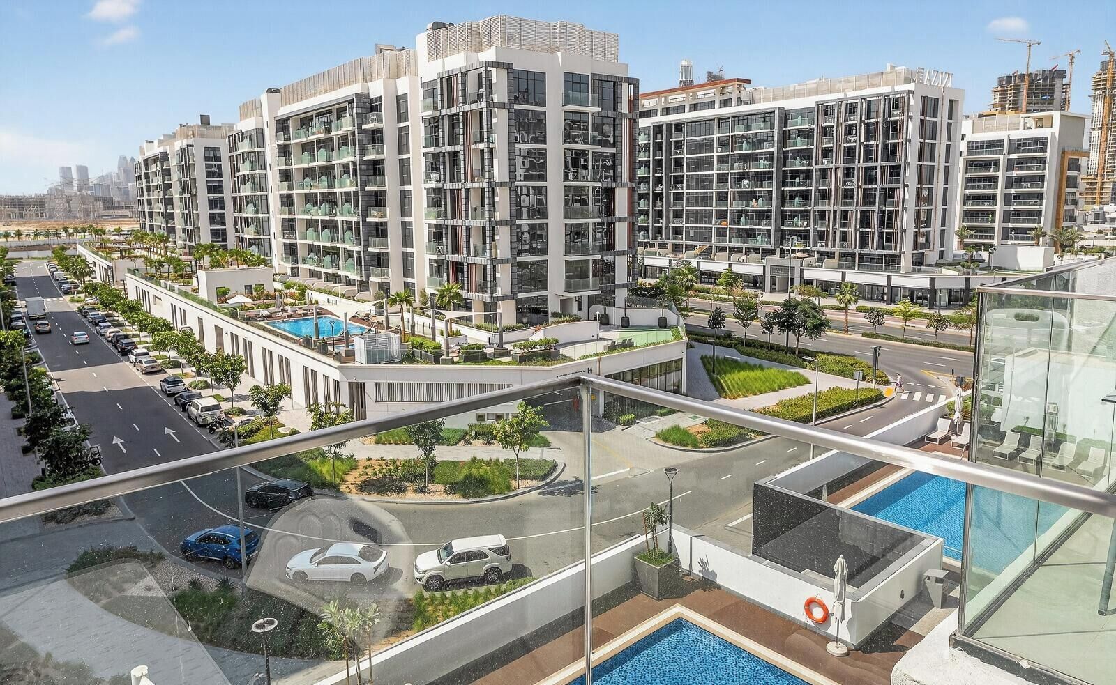 A modern apartment complex with multiple high-rise buildings, a swimming pool, and a well-maintained landscaped area.