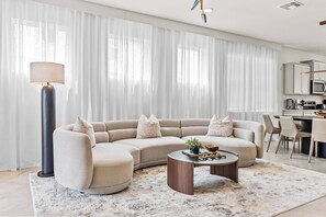 Uma sala de estar moderna com um sofá seccional, uma mesa de centro e uma luminária.