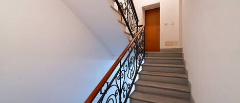 A staircase with a wooden handrail and black metal balusters.