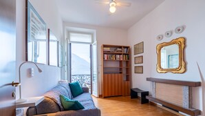 Un salon chaleureux avec un canapé, une bibliothèque, une cheminée et un grand miroir.