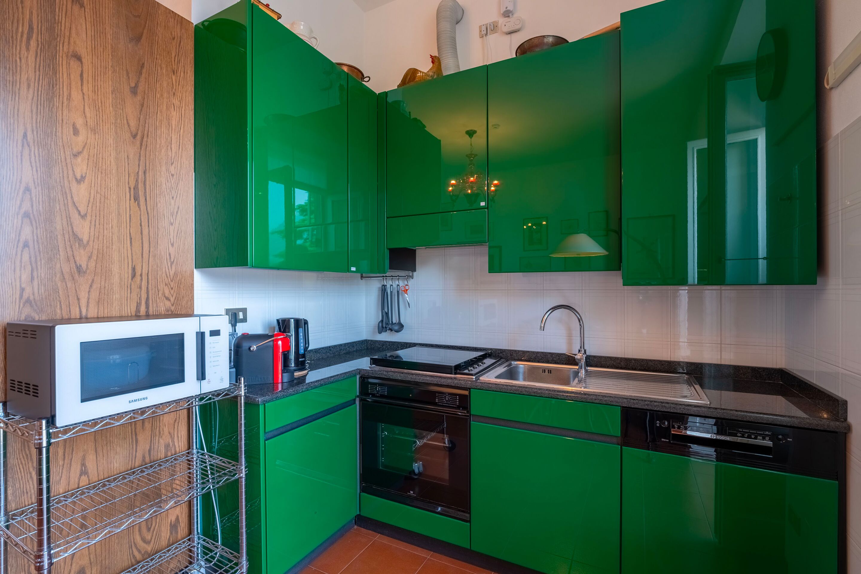 A modern kitchen with green cabinets, a microwave, a dishwasher, and a sink.