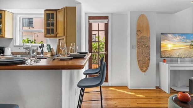 Une cuisine moderne avec des meubles en bois, un coin repas doté d’un bar et une grande décoration représentant une planche de surf.