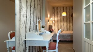 Une chambre à coucher avec un lit, une table de chevet, un miroir, une chaise et une lampe.