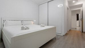 Une chambre à coucher moderne, dotée d’un grand lit, d’un dressing et d’un couloir menant à une salle de bain.
