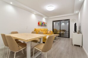 Un salon moderne comprenant un coin repas, un canapé, un téléviseur et un tableau accroché au mur.