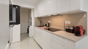 Une cuisine moderne avec des meubles blancs, un lave-linge encastré, une machine à café et un grille-pain.
