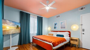 A bedroom with a bed, a nightstand, a wall-mounted TV, and a ceiling fan. - #04 Corner Unit in Mid-century Art-Déco building KingBed EnSuiteBath PetsOK (Miami Beach)