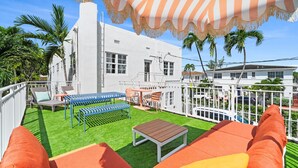 A rooftop patio with a white building in the background, a white fence, and a view of a street with cars. - #04 Corner Unit in Mid-century Art-Déco building KingBed EnSuiteBath PetsOK (Miami Beach)