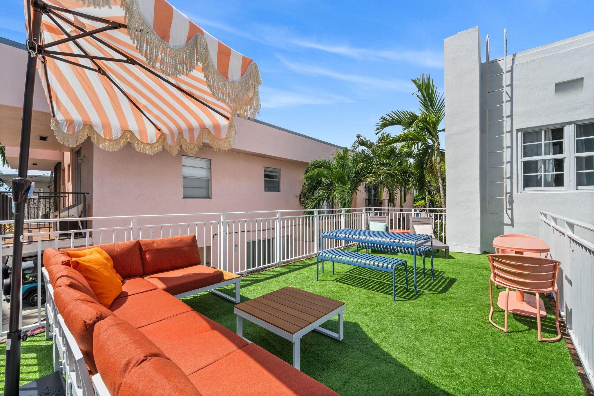Eine Terrasse mit einem Streifenverdeck, einem Sofa, einem Tisch und einem Sessel.