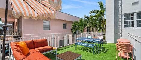 Eine Terrasse mit einem Streifenverdeck, einem Sofa, einem Tisch und einem Sessel.