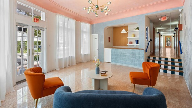 A hotel lobby with a pink ceiling, a reception desk, and a staircase leading to the upper floors. - #04 Corner Unit in Mid-century Art-Déco building KingBed EnSuiteBath PetsOK (Miami Beach)