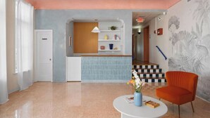 A modern interior with a kitchen area, a dining table, and a red armchair. - #05 Corner Unit in Mid-century Art-Déco Building KingBed EnSuiteBath Steps>Beach (Miami Beach)