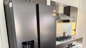 Un réfrigérateur en acier inoxydable doté d’un distributeur d’eau, un four encastré et une cuisinière à gaz, le tout intégré dans une cuisine moderne.