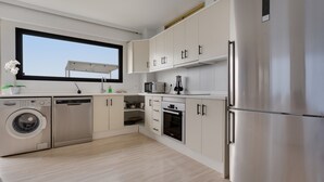A modern kitchen with stainless steel appliances, white cabinetry, and a large window. - Vacation Apartment 'Obsidian Mirador Oceano' with Sea View, Wi-Fi and Air Conditioning (Puerto de Santiago)