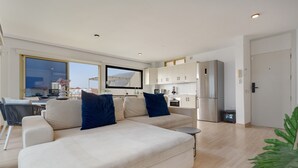 A modern living room with a sofa, a dining area, and a kitchen. - Vacation Apartment 'Obsidian Mirador Oceano' with Sea View, Wi-Fi and Air Conditioning (Puerto de Santiago)