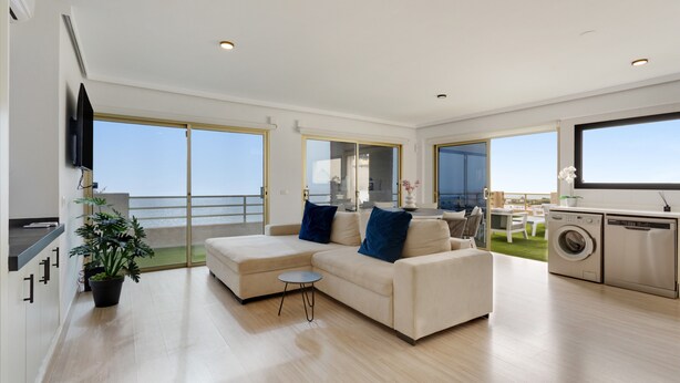 A modern living room with a sofa, a small table, and a washing machine. - Vacation Apartment 'Obsidian Mirador Oceano' with Sea View, Wi-Fi and Air Conditioning (Puerto de Santiago)
