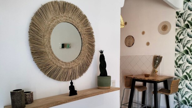 A modern interior with a round mirror, a small Buddha statue, and a wooden shelf with decorative items. - Loveroom Toulon (Toulon)