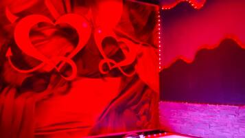 A room with a red-lit wall, a bathtub, and a stone wall.