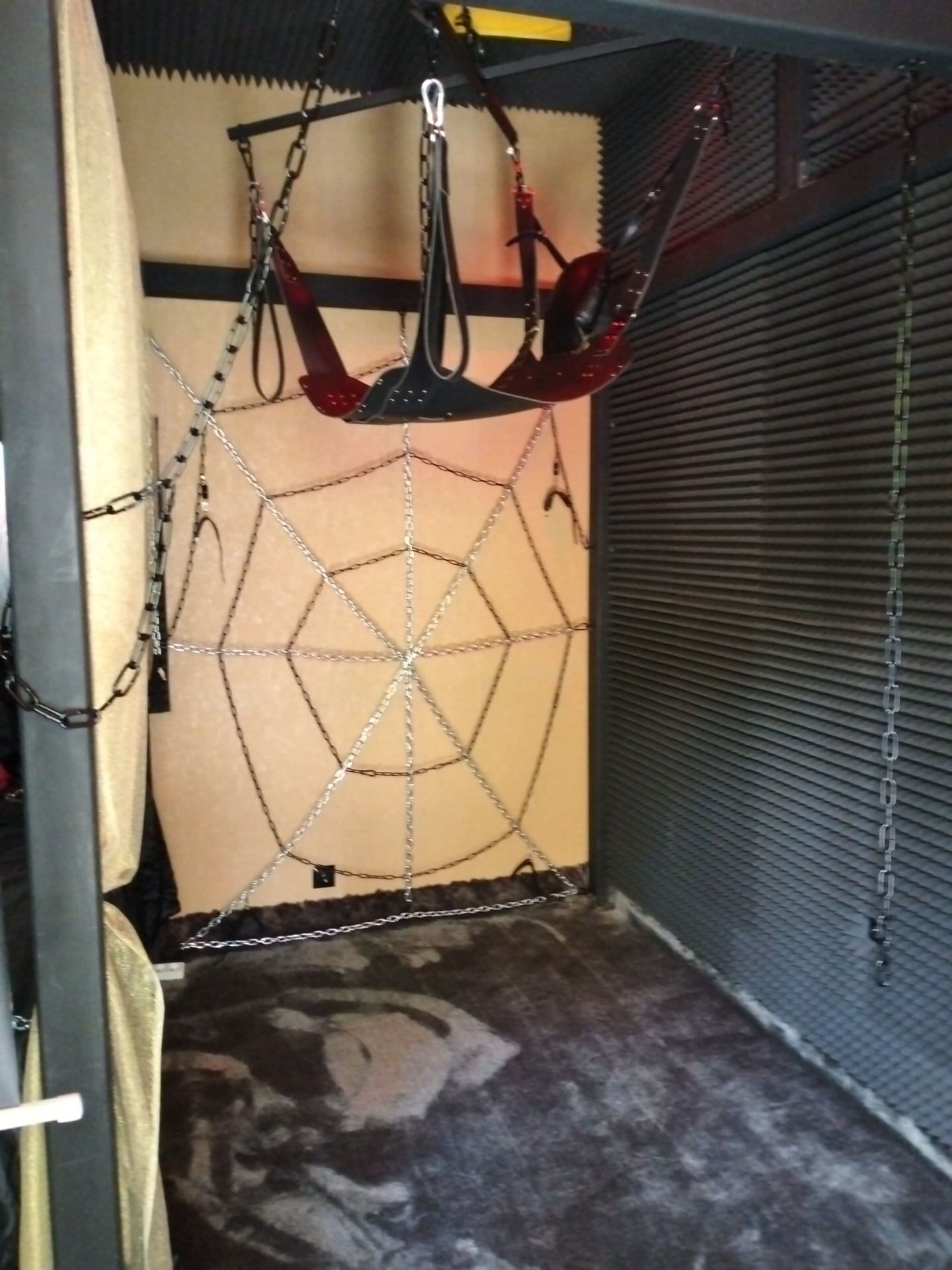 A room with a hanging exercise equipment, a closed shutter door, and a patterned floor.