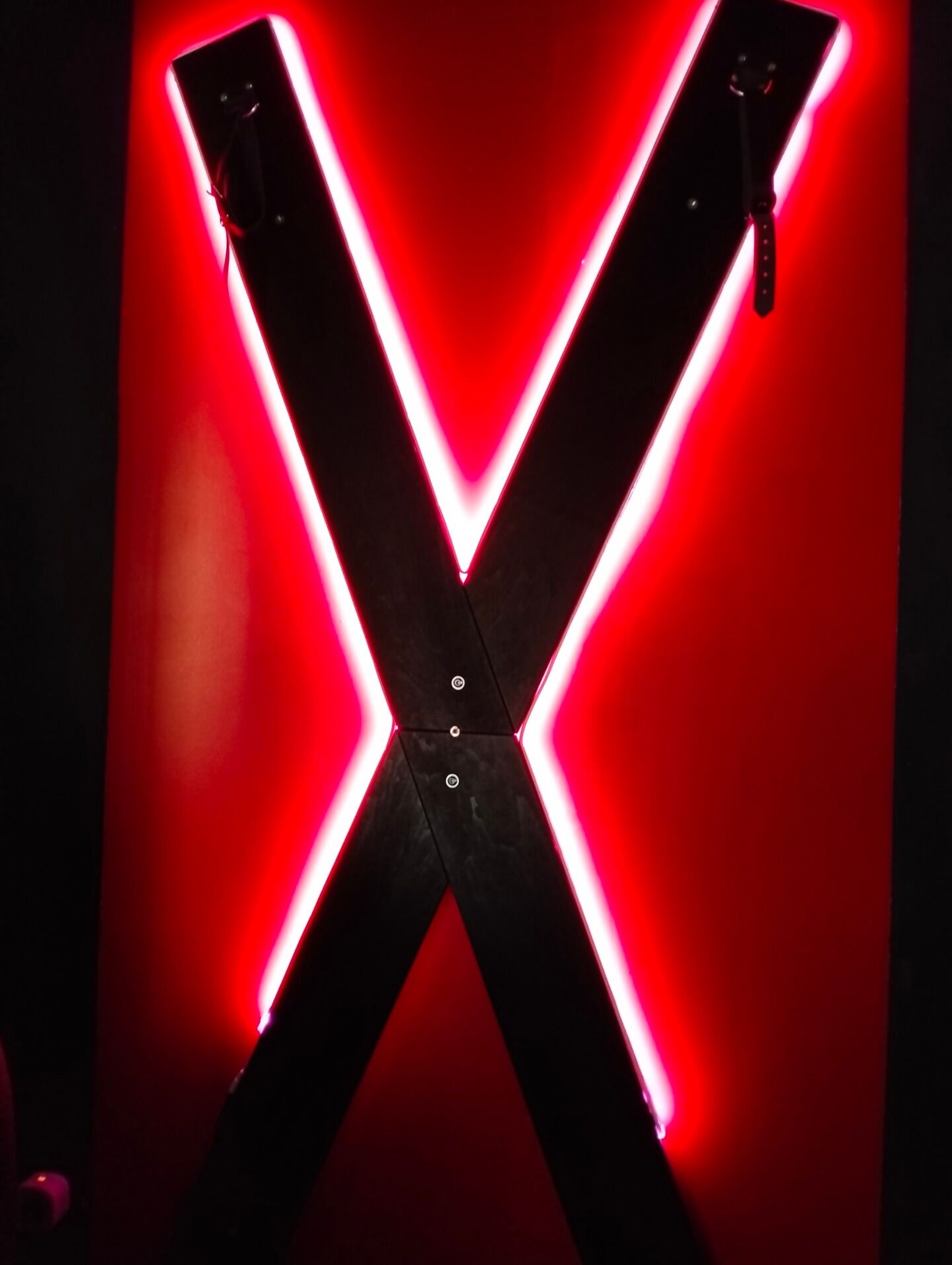 Une grande structure en forme de X, illuminée et émettant une lueur rouge.