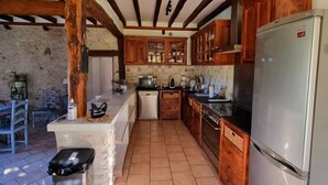 A kitchen with wooden beams, a refrigerator, and a sink. - Les Granges Indigo (Fossemagne)