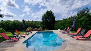 A rectangular swimming pool with a tiled deck, surrounded by lounge chairs and umbrellas. - Les Granges Indigo (Fossemagne)