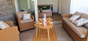 A furnished living area with wicker furniture, a coffee table, and a sofa with cushions.