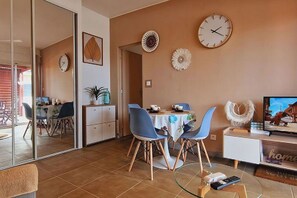 A dining area with a table, chairs, and a TV.
