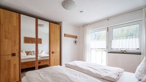Un dormitorio con cama, armario, ventana con cortinas y un pequeño adorno en la pared.